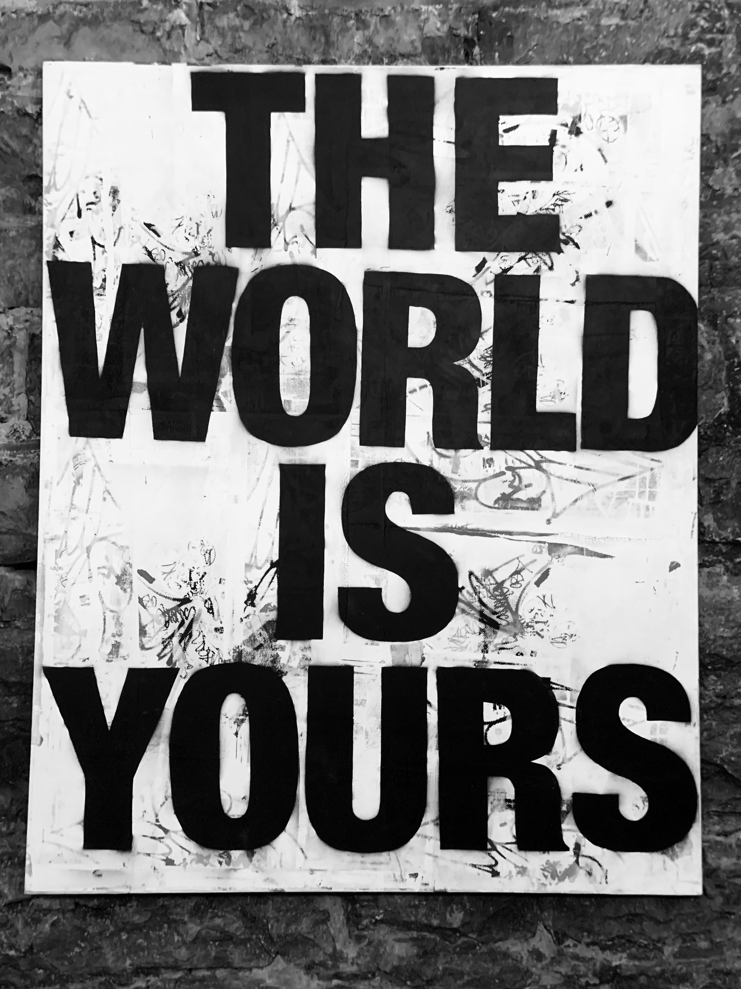 Black and white poster with the text “THE WORLD IS YOURS” on a textured background.