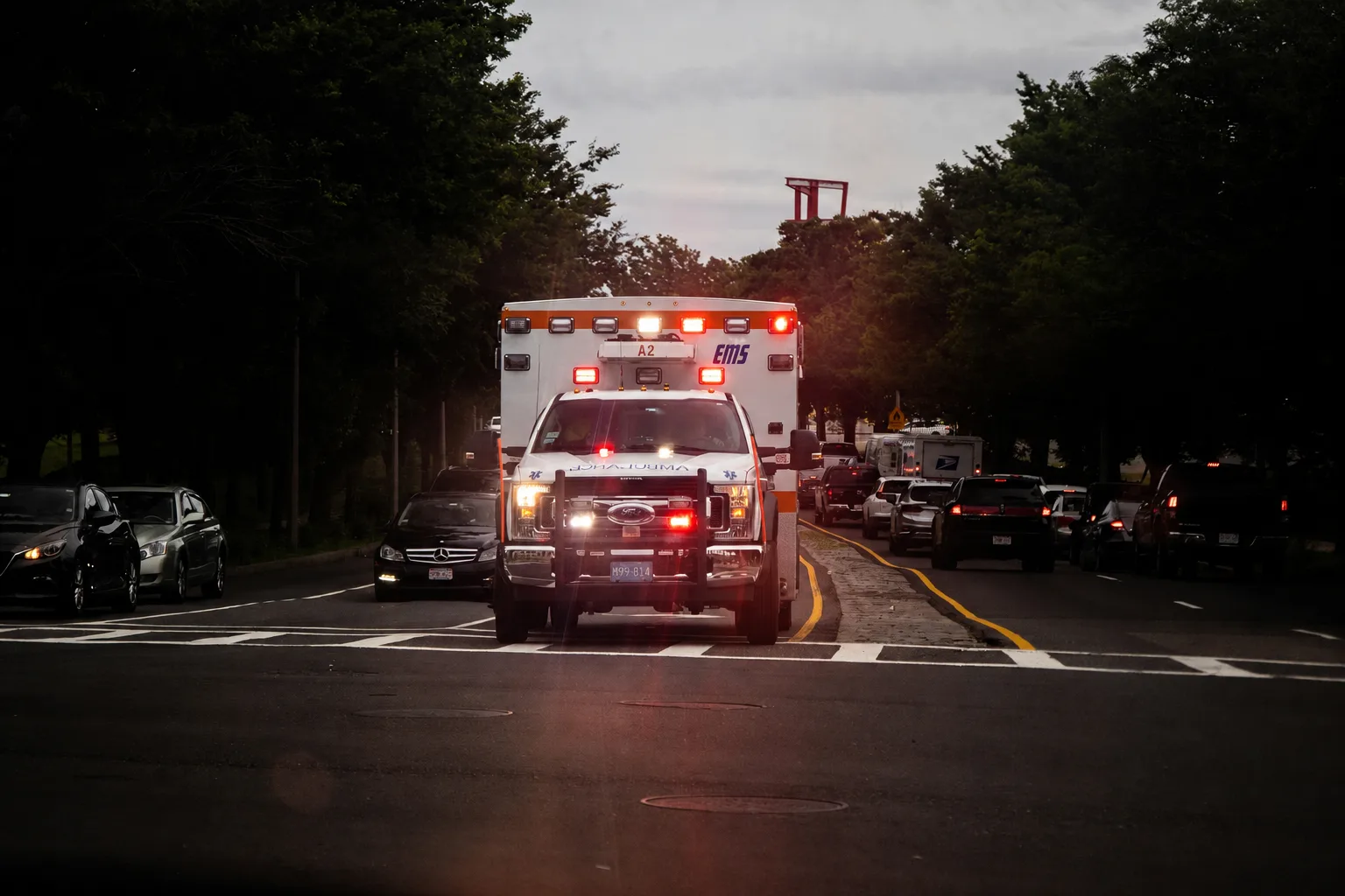 Ein amerikanischer Rettungswagen mit eingeschaltetem Blaulicht in der Abenddämmerung, dahinter stehender Verkehr auf einer vierspurigen Straße